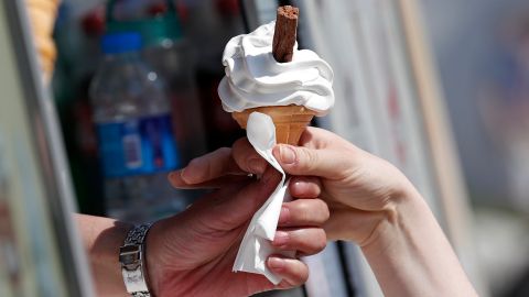 A customer (R) takes a "99" ice cream from a vendor as people enjoy the hot weather in Richmond, south west London on May 7, 2018. - Temperatures on Monday were predicted to reach 29C (84.2F) in parts of the south east of England, as people enjoyed the three-day bank holiday weekend. (Photo by Adrian DENNIS / AFP)        (Photo credit should read ADRIAN DENNIS/AFP/Getty Images)