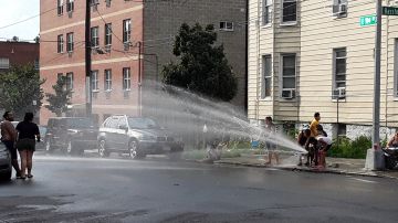 Altas temperaturas obliga a muchos a refrescarse en las calles, como esta familia en El Bronx.