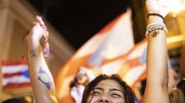 Una joven celebra la salida del gobernador de Puerto Rico, Ricardo Rosselló, en el exterior de La Fortaleza.