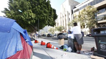 Una desamparada remueve sus cosas de la calle que van a limpiar en Los Ángeles.