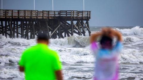 Personas miran el oleaje desde Main Street Pier de Daytona Beach, Florida,