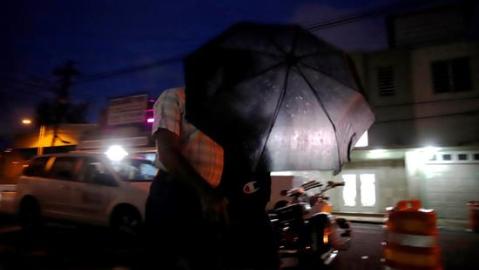 Dos ciudadanos se cubren con una sombrilla durante el paso de la tormenta Karen, en San Juan.