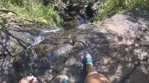 La joven se resbala mientras se encuentra parada al filo de una piedra.