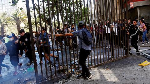 Manifestantes sacan una reja este lunes para ser lanzada a una barricada en el centro de la capital, sector Plaza Italia.