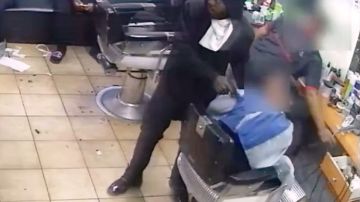 El ladrón apuntando a la victima en la silla del barbero
