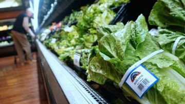 Un hombre compra verduras al lado de lechuga romana almacenada y a la venta en un supermercado en Los Ángeles, California.