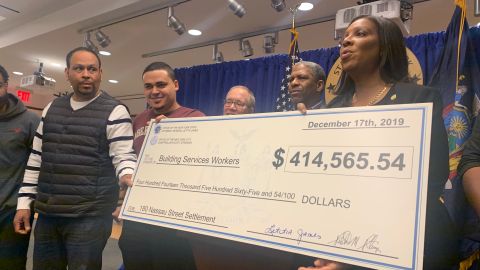 La fiscal general Letitia James muestra el cheque por más de  $400,000, en salarios recuperados para trabajadores de edificios.