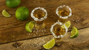 Tequila shots with lime and salt on the wooden background top vi