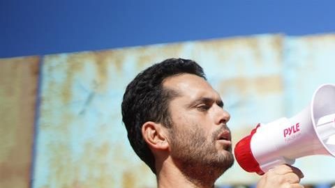 El fundador del Jardín Binacional, Daniel Watman, habla por megáfono el 12 de enero cerca de la valla que separa San Diego (California) de Tijuana (México).