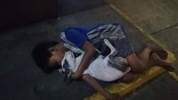 Niño sin hogar duerme con su perro en la calle.