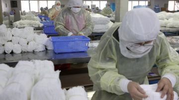 Trabajadores en una fábrica de mascarillas en Nantong (China)