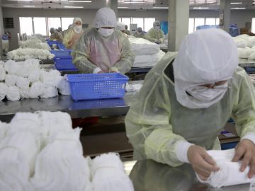 Trabajadores en una fábrica de mascarillas en Nantong (China)