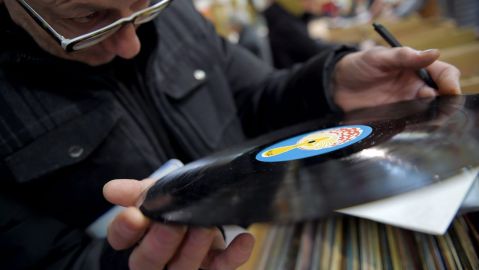 Un hombre observa atentamente un disco de vinil antes de comprarlo