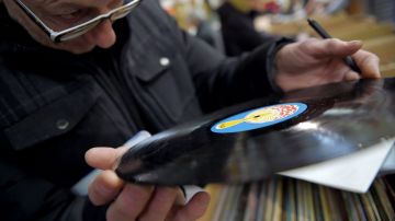 Un hombre observa atentamente un disco de vinil antes de comprarlo
