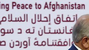 El representante especial de EEUU Zalmay Khalilzad, da la mano al cofundador del Talibán, Mullah Abdul Ghani Baradar.