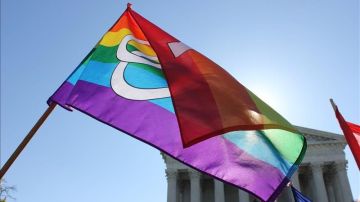Una bandera gay ondea en una multitudinaria concentración a las puertas del Tribunal Supremo de EEUU.