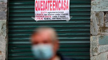 Un hombre en Quito camina frente a un letrero que pide permanecer en casa.