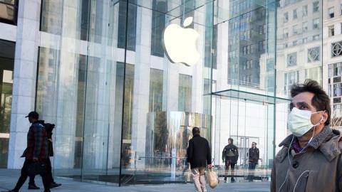 Un hombre con una máscara protectora pasa junto a una Apple Store cerrado, en la Quinta Avenida de Manhattan.
