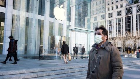 Un hombre con una máscara protectora pasa junto a una Apple Store cerrado, en la Quinta Avenida de Manhattan.