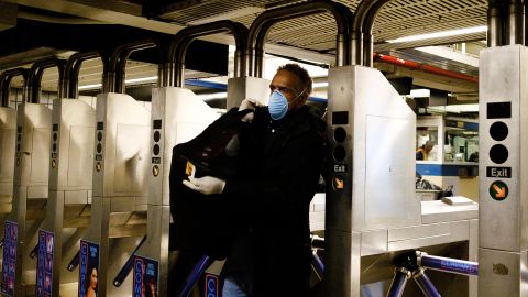 Un hombre con una máscara facial ingresa a la estación de metro de Times Square en NY.