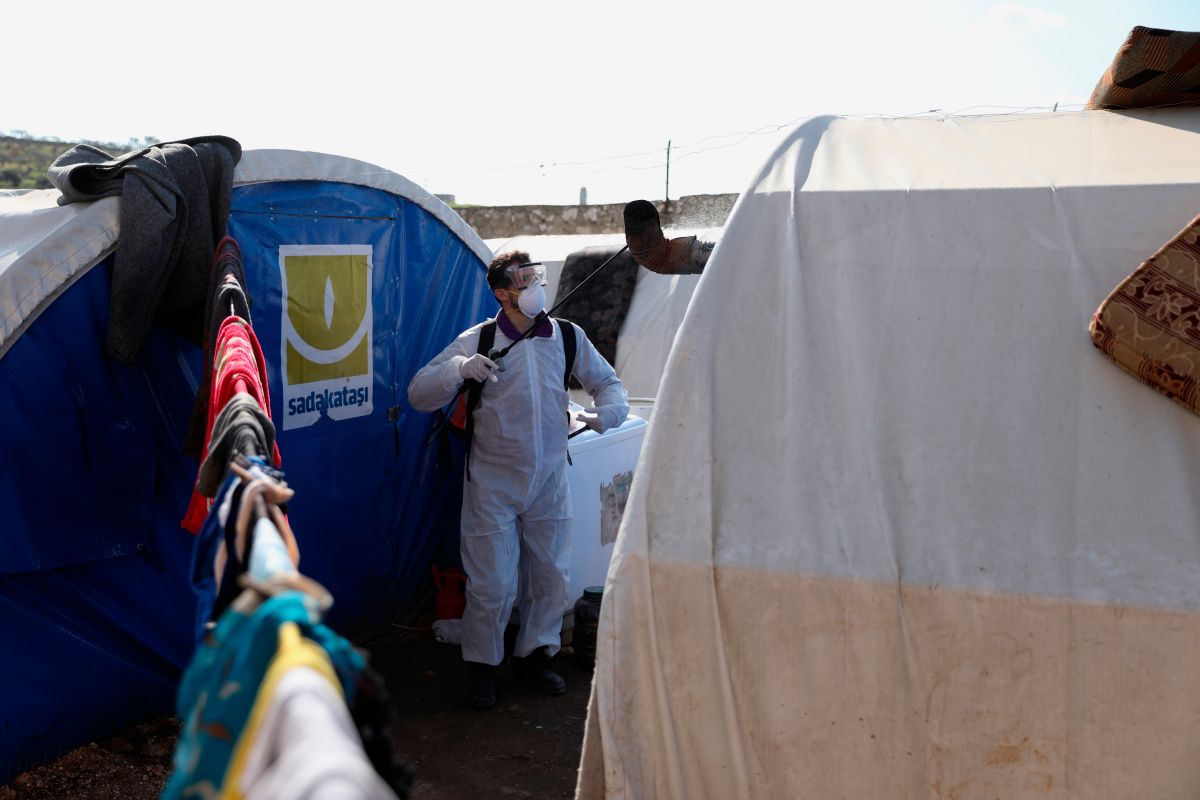 Personal sanitario desinfecta un campamento de desplazados por la guerra.