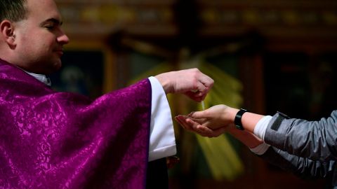 Un feligrés comulga de las manos del sacerdote Laszlo Monostori en la iglesia de Santa Margarita en Budapest, Hungría.