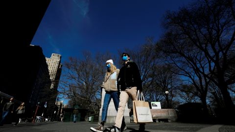 Una pareja con mascarilla camina por Central Park., NYC.