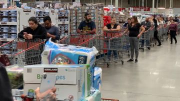 Los clientes esperan en fila para comprar agua y otros suministros en una tienda Costco en Los Ángeles.