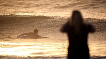 Un surfista entra al mar al atardecer. Foto de archivo.