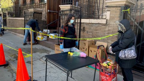 Una mujer llena su carrito con comida en una despensa de alimentos en Chelsea, donde esta semana se registraron largas filas de personas necesitadas.