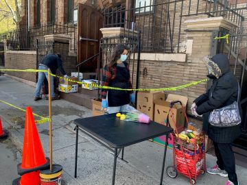 Una mujer llena su carrito con comida en una despensa de alimentos en Chelsea, donde esta semana se registraron largas filas de personas necesitadas.