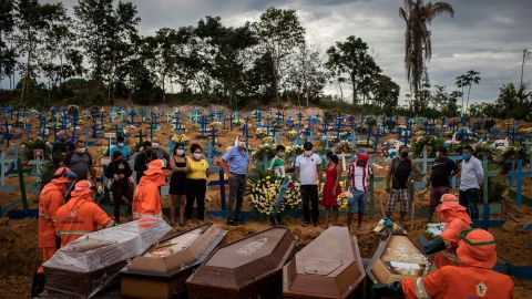 -FOTODELDÍA- BRA01. MANAOS (BRASIL), 23/04/2020.- Un grupo de personas asiste a un sepelio en donde los ataúdes son colocados en una tumba colectiva, en un área abierta en el cementerio Nossa Senhora Aparecida, ubicado en la ciudad de Manaos, Amazonas. La nueva sección del cementerio se abrió después de las muertes causadas por COVID-19 que colapsaron el sistema funerario de la ciudad. EFE / Raphael Alves