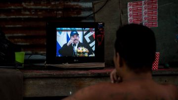 Un hombre observa la pantalla de un televisor en donde aparece el presidente de Nicaragua, Daniel Ortega.