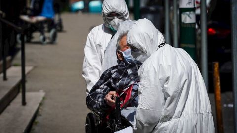 Un equipo médico totalmente protegido traslada a un paciente de coronavirus.