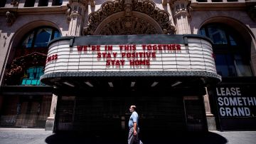 Los Angeles (United States), 27/05/2020.- A man wearing a face mask walks past the Million Dollar Theater which front reads 'We're In This Together, Stay Positive, Stay Home', amid the coronavirus pandemic in Los Angeles, California, USA, 27 May 2020. Los Angeles County officials have announced on 26 May, moving forward with the reopening of the County, with restaurants allowed to open with restrictions. (Abierto, Estados Unidos) EFE/EPA/ETIENNE LAURENT
