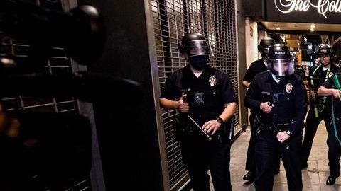 Una mujer cae de su bicicleta mientras la Policía de L.A. le bloquea el paso.
