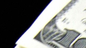 A money changer holds a wad of USD bills
