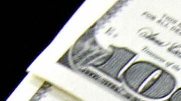 A money changer holds a wad of USD bills