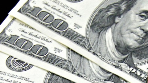 A money changer holds a wad of USD bills