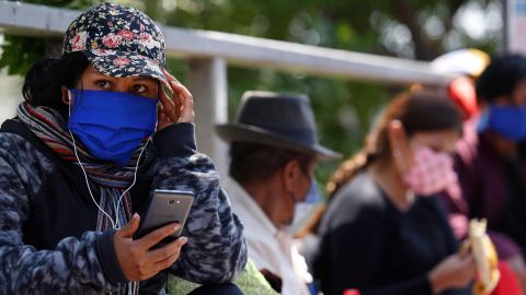 En la imagen, un grupo de personas aguarda junto a una terminal de buses en Lima. EFE/