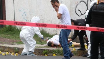 Elementos de la fiscalía de Ciudad de México levantan el cuerpo de uno de los hombres asesinados el martes.