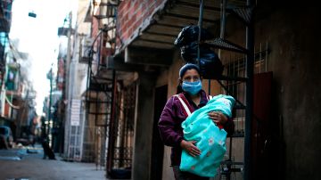 Una mujer  camina con su bebé  por una calle de la Villa 31, una de las más peligrosas de  Buenos Aires.