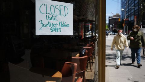 NEW YORK CITY- MAY 12: People walk through a shuttered business district in Brooklyn on May 12, 2020 in New York City. Across America, people are reeling from the loss of jobs and incomes as unemployment soars to historical levels following the COVID-19 outbreak. While some states are beginning to re-open slowly, many business are struggling to find a profit with the news restrictions and a population that is fearful of the contagious virus. (Photo by Spencer Platt/Getty Images)