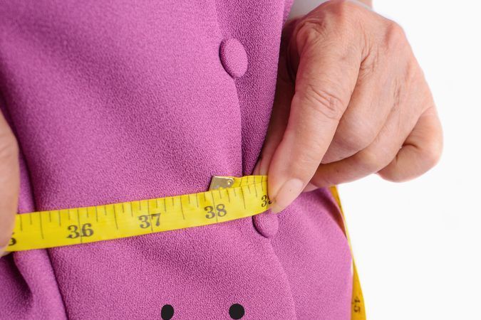 Mujer frustrada por no reducir centímetros al medirse con un metro