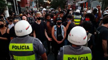 Manifestantes levantan sus brazos y permanecen quietos frente a unos policías durante una protesta contra el presidente de Brasil, Jair Bolsonaro en Sao Paulo.
