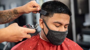 Un joven en Texas lleva cubrebocas mientras le cortan el pelo.