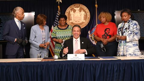 Cuomo firma la ley acompañado del reverendo Al Sharpton, los dos líderes de la Legislatura estatal, y varias madres de fallecidos por brutalidad policial, como la mamá de Eric Garner.