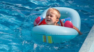Aunque el niño esté en la piscina con los flotadores de brazos y el de forma de dona, éste no está seguro.