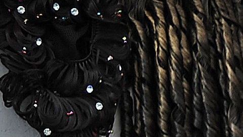 Una mujer ayuda a otra a chequear una extensión de cabello en un mercado.