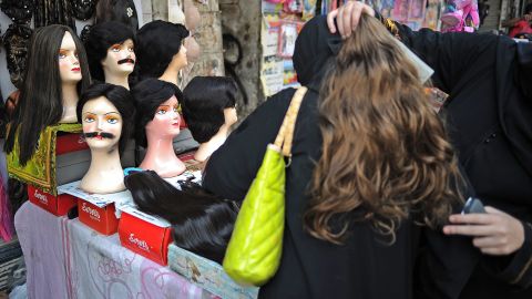 Una mujer ayuda a otra a chequear una extensión de cabello en un mercado.